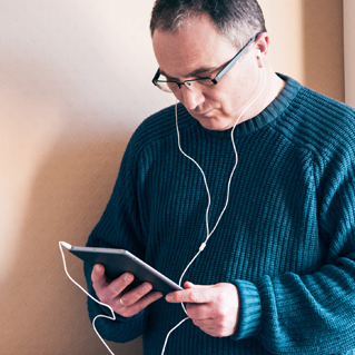 Arden University student listening to tutorial on his tablet