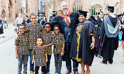 Arden University graduate with family and tutor