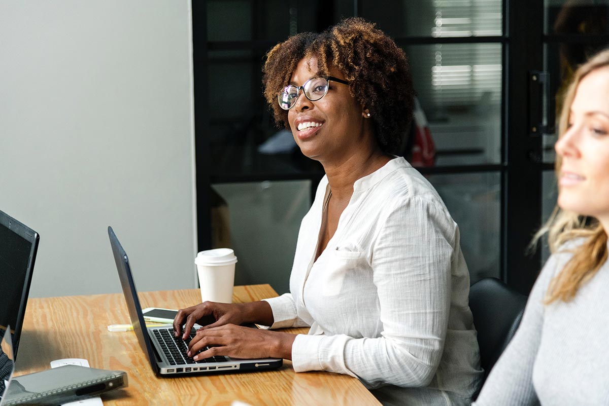 Woman with a laptop looking at colleagues in a meeting