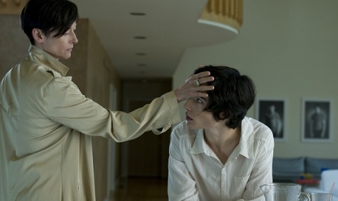 Woman with short hair with hand on forehead of teenage boy